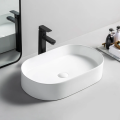 Biała owalna umywalka ceramiczna VICTORIA 46 Veldman z czarną baterią na jasnym blacie przed lustrem