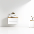 Szafka umywalkowa wisząca LINDA Veldman w kolorze białym, z blatem w kolorze dąb, z białą umywalką oraz złotą baterią ścienną na tle jasnej ściany