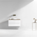 Szafka umywalkowa wisząca LINDA Veldman w kolorze białym, z blatem w kolorze kaszmir, z białą umywalką oraz złotą baterią ścienną na tle jasnej ściany