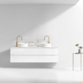 Szafka umywalkowa wisząca LINDA Veldman w kolorze białym, z białym blatem, z białymi umywalkami oraz ze złotymi bateriami ściennymi na tle jasnej ściany