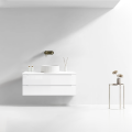 Szafka umywalkowa wisząca LINDA Veldman w kolorze białym z białą umywalką oraz złotą baterią ścienną na tle jasnej ściany