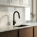 Nowoczesna kuchnia z marmurowym blatem, stalowym zlewem i czarną baterią SIMONA przy oknie, jasne szafki, minimalistyczny styl.