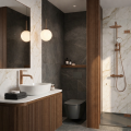 Nowoczesna łazienka z umywalką nablatową, drewnianą szafką, armaturą w kolorze miedzi, prysznicem walk-in oraz marmurowymi i ciemnymi płytkami.