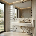 Luksusowa łazienka z marmurową ścianą,  dużym lustrem, beżową umywalką nablatową VERONA i subtelną złotą armaturą w ciepłej tonacji