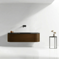 Minimalistyczna łazienka z wiszącą szafką VERRA Veldman w kolorze ORZECH z czarną umywalką z konglomeratu, czarną baterią ścienną oraz stojącym stolikiem z dekoracyjną rośliną
