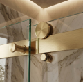 Nowoczesna kabina prysznicowa z marmurowymi ścianami i złotymi prowadnicami, oświetlona ciepłym światłem - zbliżenie na rolki