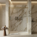 Nowoczesne drzwi prysznicowe z profilami w kolorze złotym szczotkowanym, marmurową ścianą i minimalistycznym wystrojem łazienki