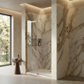 Nowoczesne drzwi prysznicowe z profilami w kolorze złotym szczotkowanym, marmurową ścianą, dużym oknem i minimalistycznym wystrojem łazienki
