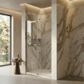 Nowoczesne drzwi prysznicowe z profilami w kolorze złotym szczotkowanym, marmurową ścianą, dużym oknem i minimalistycznym wystrojem łazienki