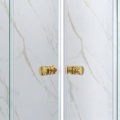 Zbliżenie na uchwyty drzwi kabiny prysznicowej w kolorze złotym na tle jasnej, marmurowej ściany..png