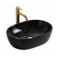 Czarna owalna umywalka w połysku nablatowa ANNA Veldman ze złotą baterią