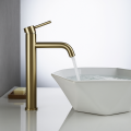 Bateria umywalkowa w kolorze szczotkowanego złota z pojedynczym uchwytem, z której wypływa strumień wody, zamontowana przy białej umywalce Veldman
