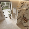 Luksusowa łazienka z marmurowymi ścianami, drzwiami prysznicowymi COMO w kolorze złoty szczotkowany, dużym oknem, rośliną w donicy i ciepłym oświetleniem - widok z góry