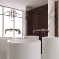 Bateria umywalkowa ścienna Costa Nikiel nad białą cylindryczną umywalką, w eleganckiej aranżacji łazienki z dużym lustrem.